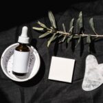 Butelka serum z pipetą i płytka gua sha na czarnym tle